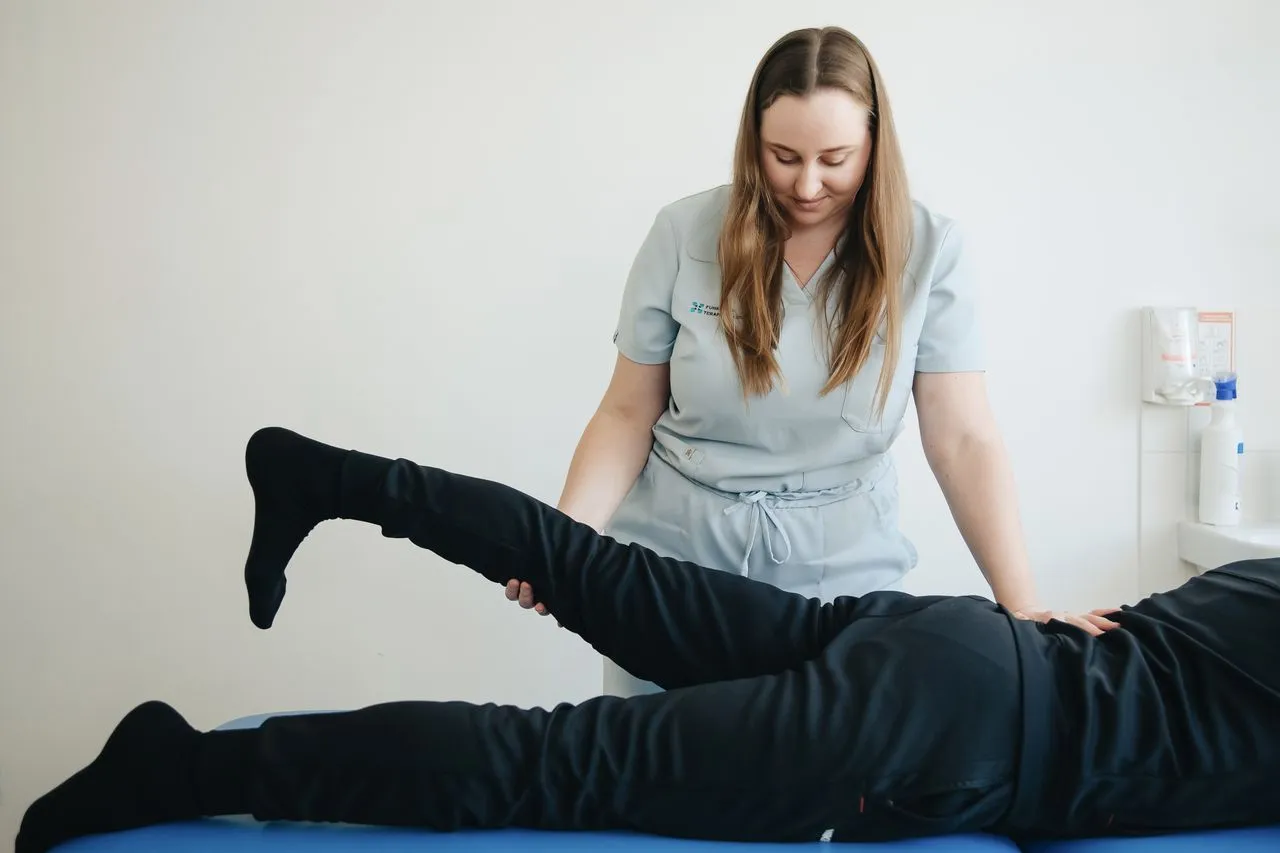 Physiotherapist guiding a patient’s hip and leg stretch