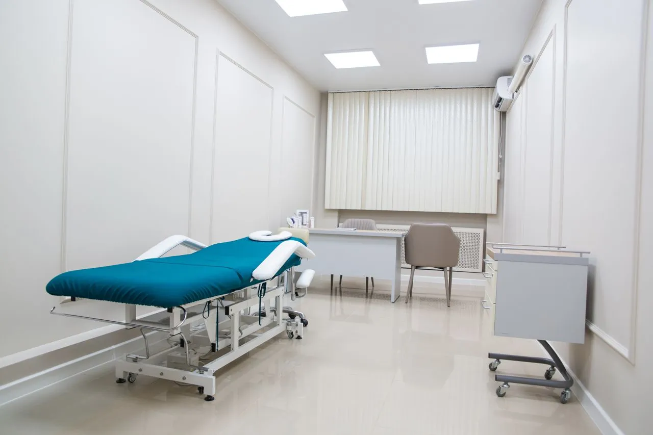 Bright treatment room with an adjustable treatment bed and desk